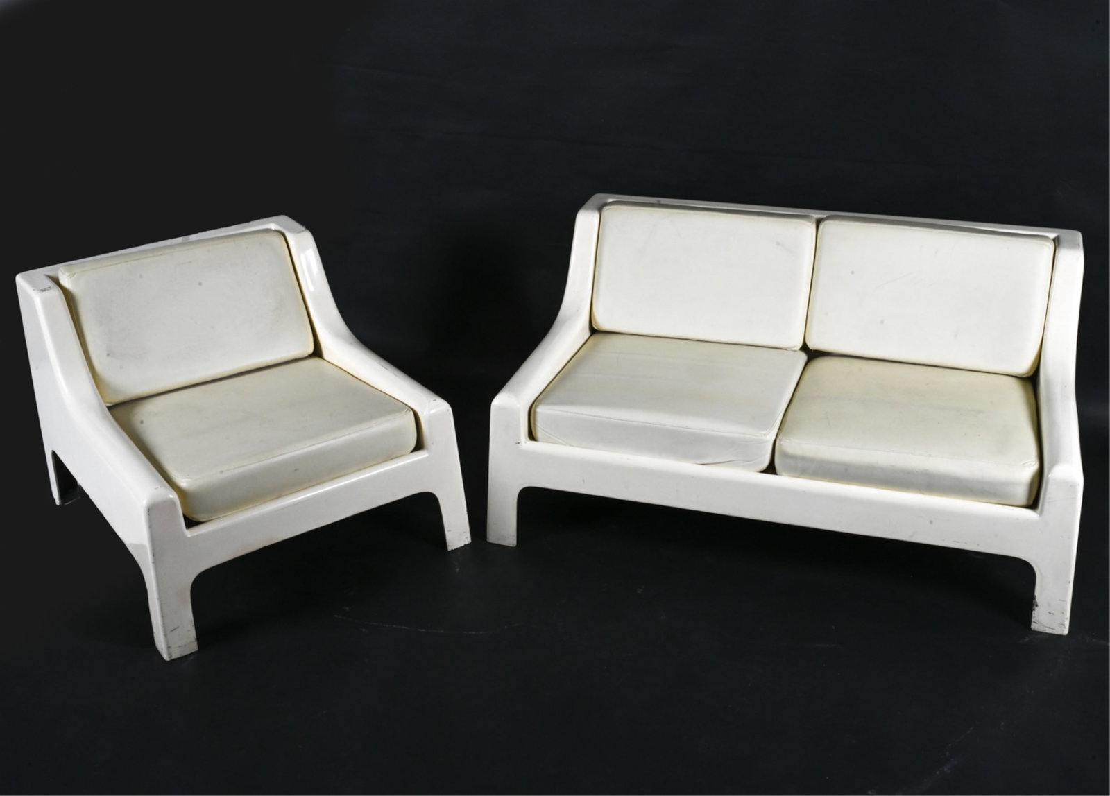 ATTR. CAPELLINI MOLDED FIBERGLASS SUITE, C. 1970'S: Vintage molded fiberglass club chair and love seat. C. 1970s. Dimensions: (2-seater) H 26" x W 52" x D 32" x SH 15.5" (Chair) H 26" x W 30" x D 32" Condition: Dings, nicks, scuffs and marks to fibergl