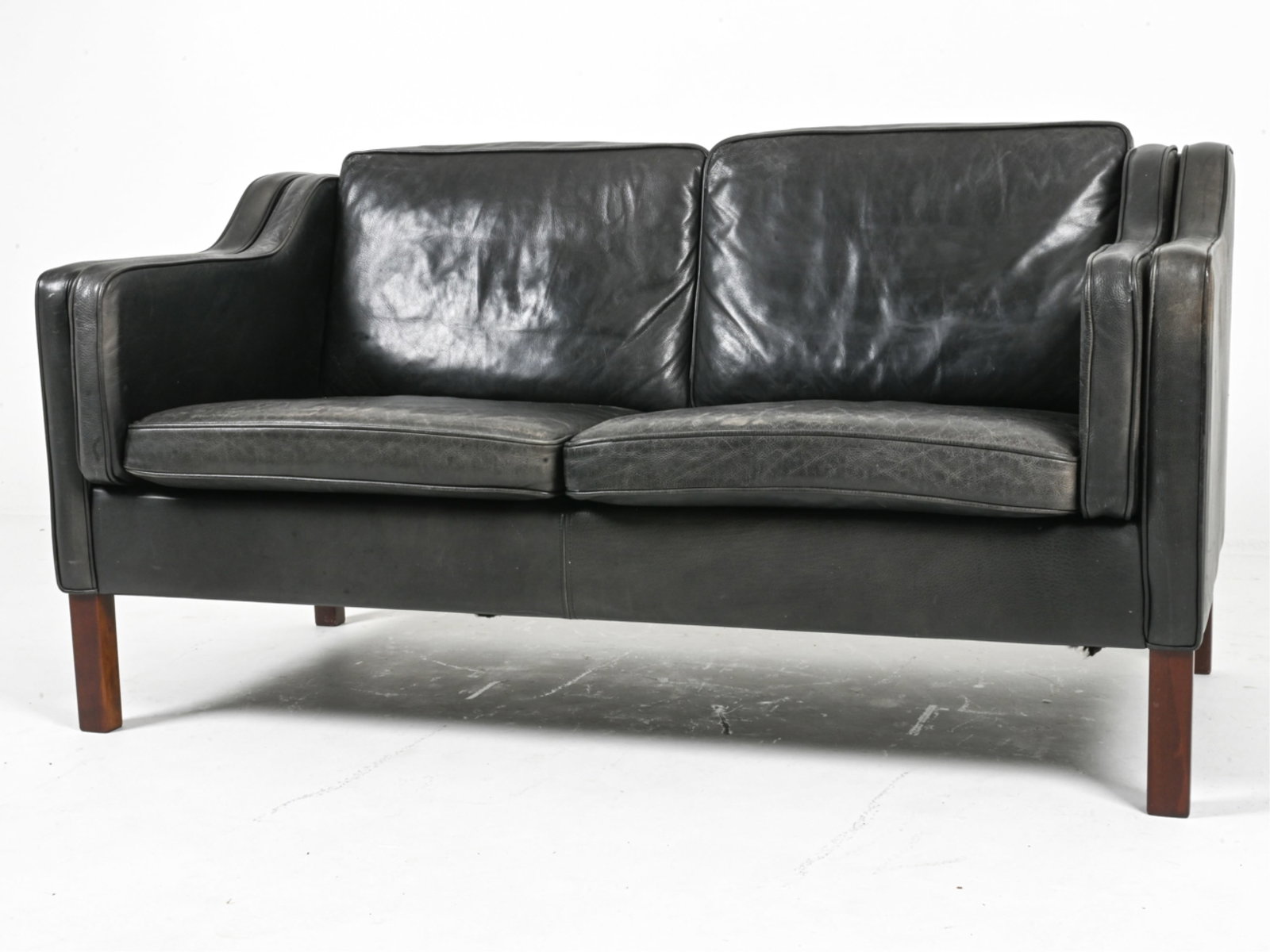 MANNER OF BORGE MORGENSEN DANISH LEATHER SOFA: Danish, circa 1960's. Dimensions: H 31.25" x W 59" x D 29". SH 17.5". Condition: Areas of discoloration on arms, cushions. DME 035
