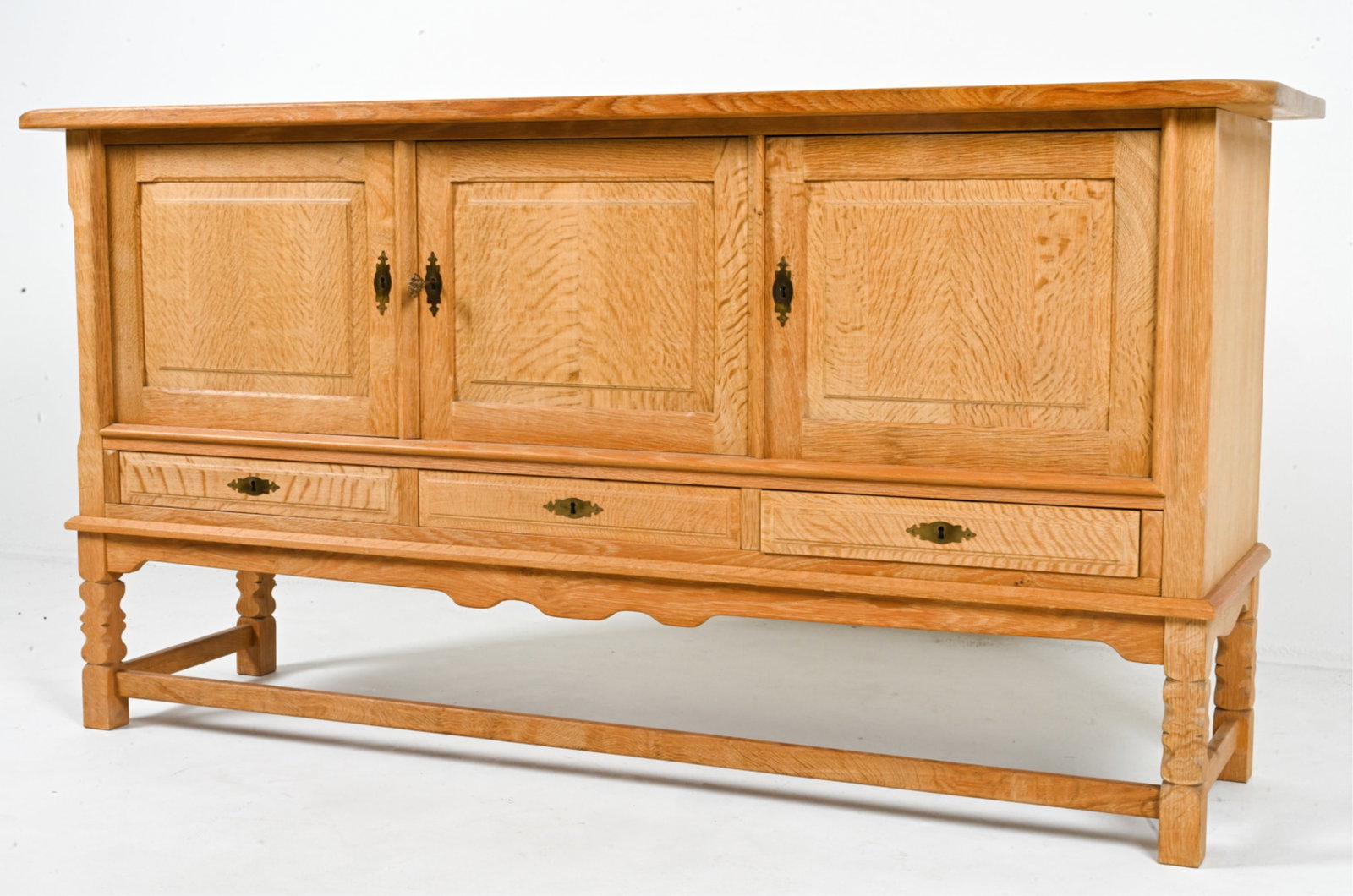 MANNER OF HENNING KJAERNULF OAK SIDEBOARD: Three keys included. Danish, circa 1970s. Dimensions: H 36" x W 69" x D 19". Condition: Minor spots of surface soiling and discoloration. DME 031