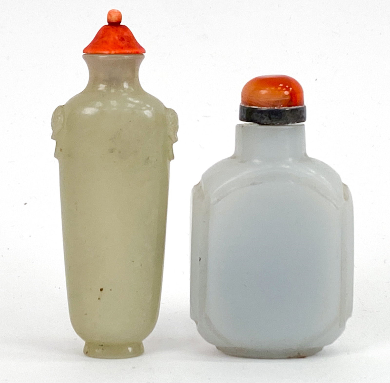 (2) CHINESE CARVED JADE SNUFF BOTTLES: *One with geometric decorations the other with masks on shoulders. One with a carnelian lid, other stained bone. Dimensions: (Taller) H 3.5" x W 1.25" x D .75" Condition: Some glue residue. Some dirt.