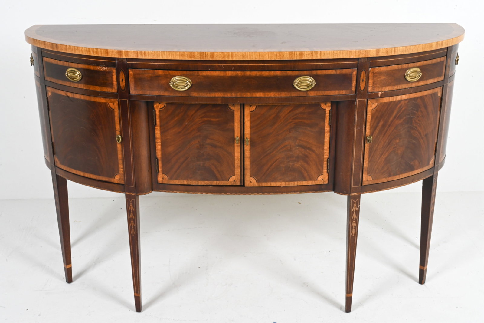 FEDERAL STYLE INLAID MAHOGANY SIDEBOARD BY HICKORY: Demilune form with contrasting satinwood banding atop single long drawer flanked by two short drawers surmounting inset compartment enclosed by flame mahogany and satinwood. Veneered double doors flan