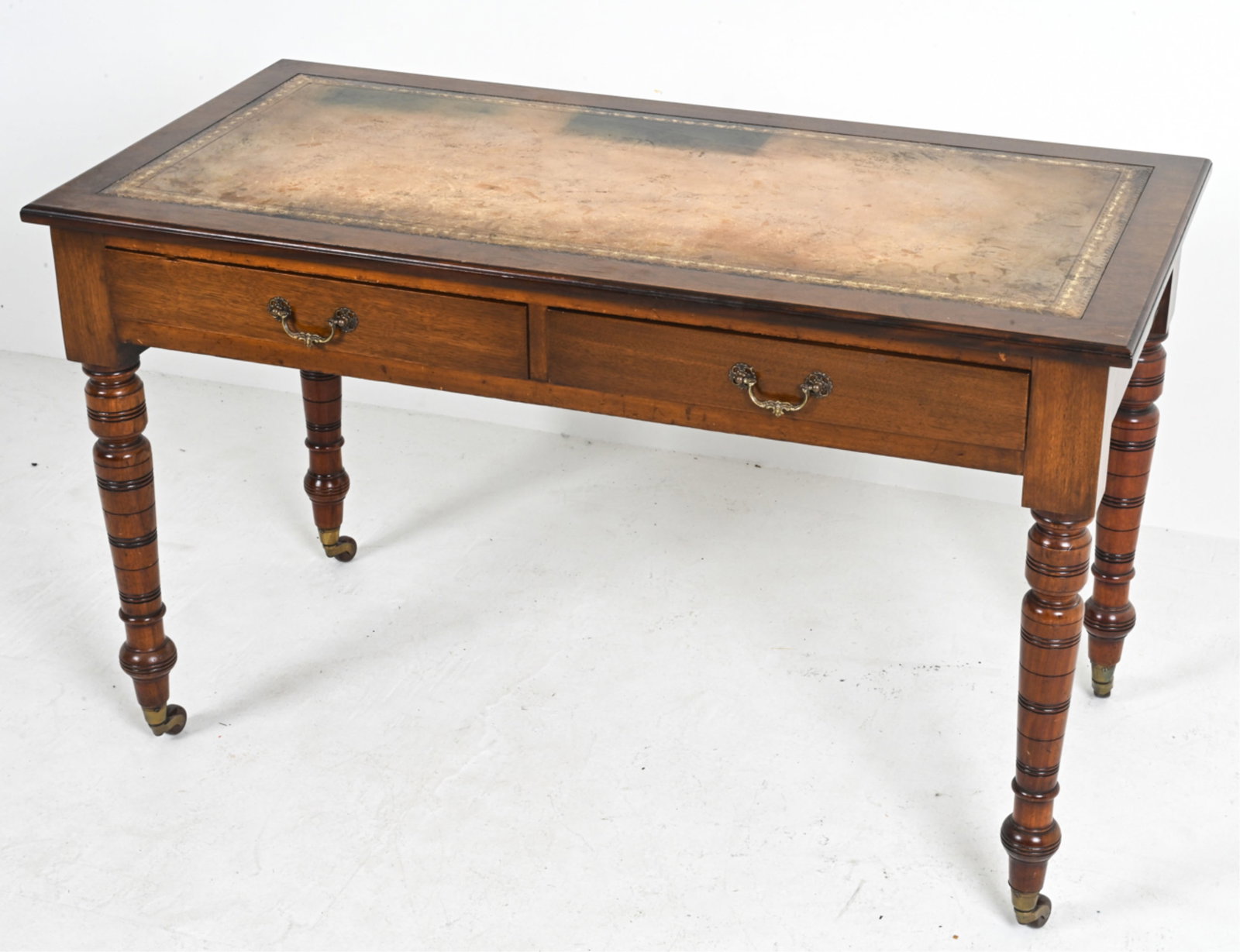 ANTIQUE MAHOGANY DESK WITH LEATHER TOP: Victorian era mahogany desk with tooled leather top. Two drawers with brass pulls, caster wheels. Dovetailed hinges on drawers. Late 19th or early 20th century. Dimensions: H 29" x W 49" x D 23". Cond