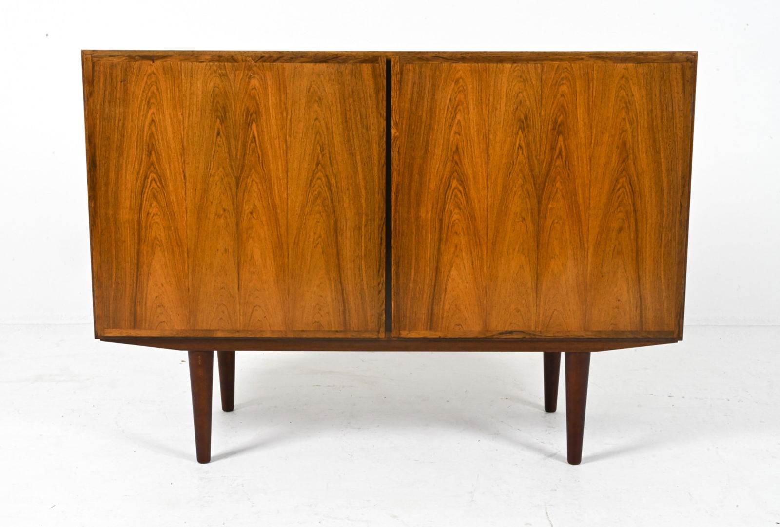ATTR. GUNNI OMANN FOR OMANN JUN ROSEWOOD CABINET: Denmark, c. 1960's-1970's. Dimensions: H 33" x W 47.25" x D 16.5". Condition: Legs do not appear to be original. Sun fading throughout. Scattered dings and scuffs. Wear consistent with age and use. DM