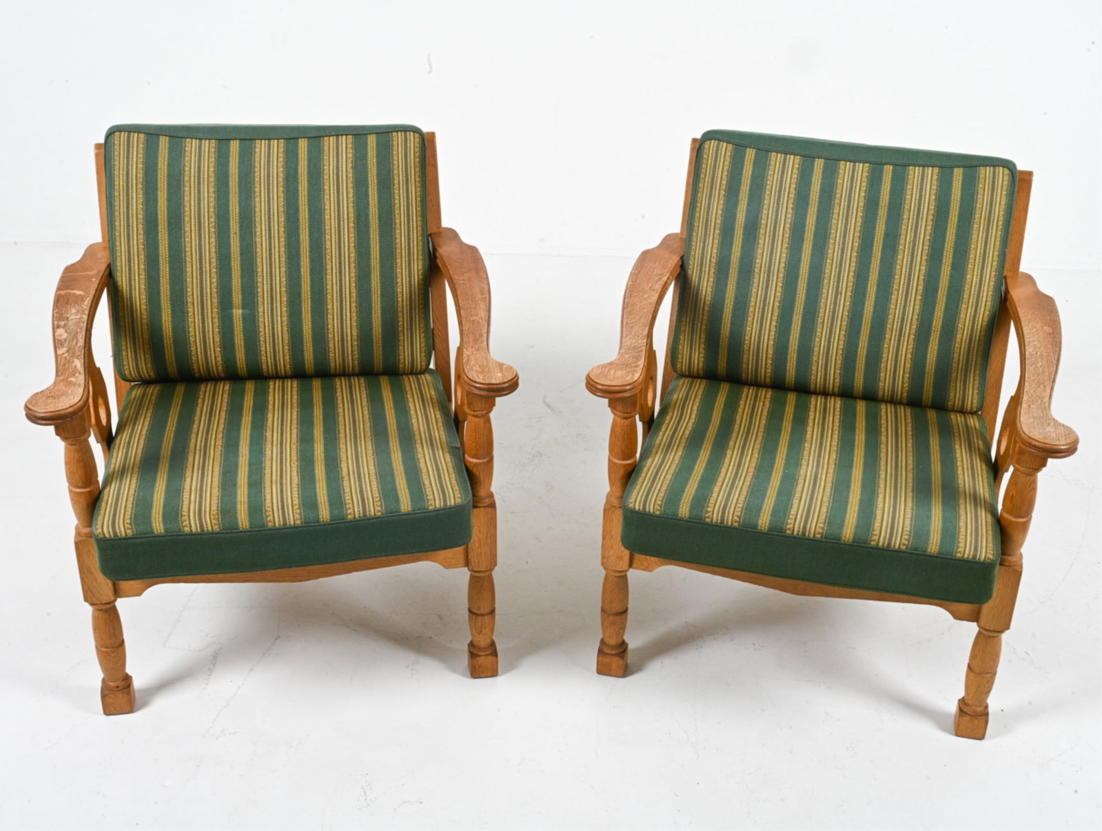 (2) MANNER OF HENNING KJAERNULF OAK LOUNGE CHAIRS: Denmark, circa 1960's. Dimensions: H 29" x W 27" x D 26.75". SH 16". Condition: Spots of discoloration to wood on arms. Wear expected from age and use. C075