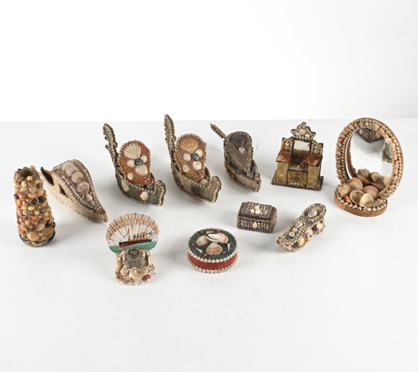 SAILOR FOLK ART SHELL-ENCRUSTED OBJECTS: Includes several decorative objects and vanity items such as mirror, boxes, vase, etc. Dimensions: Mirror H 9.25" x W 6.75". Condition: Minor surface soiling, some loose shells. Wear consistent with a