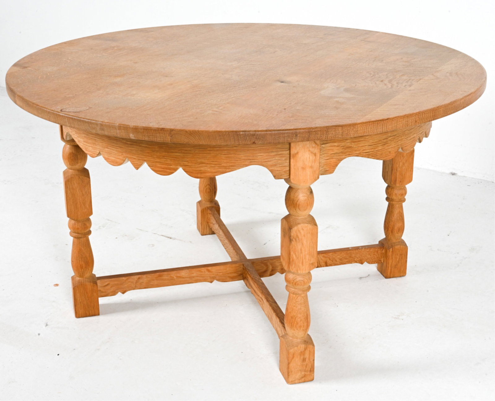 OAK COFFEE TABLE BY HENRY KJAERNULF: Carved apron with turned legs, stretcher base. Denmark, circa 1970's. Dimensions: H 21.25" x Dia. 28.25". Condition: Faint water ring on top, some areas of wear and fading. Wear consistent with age an