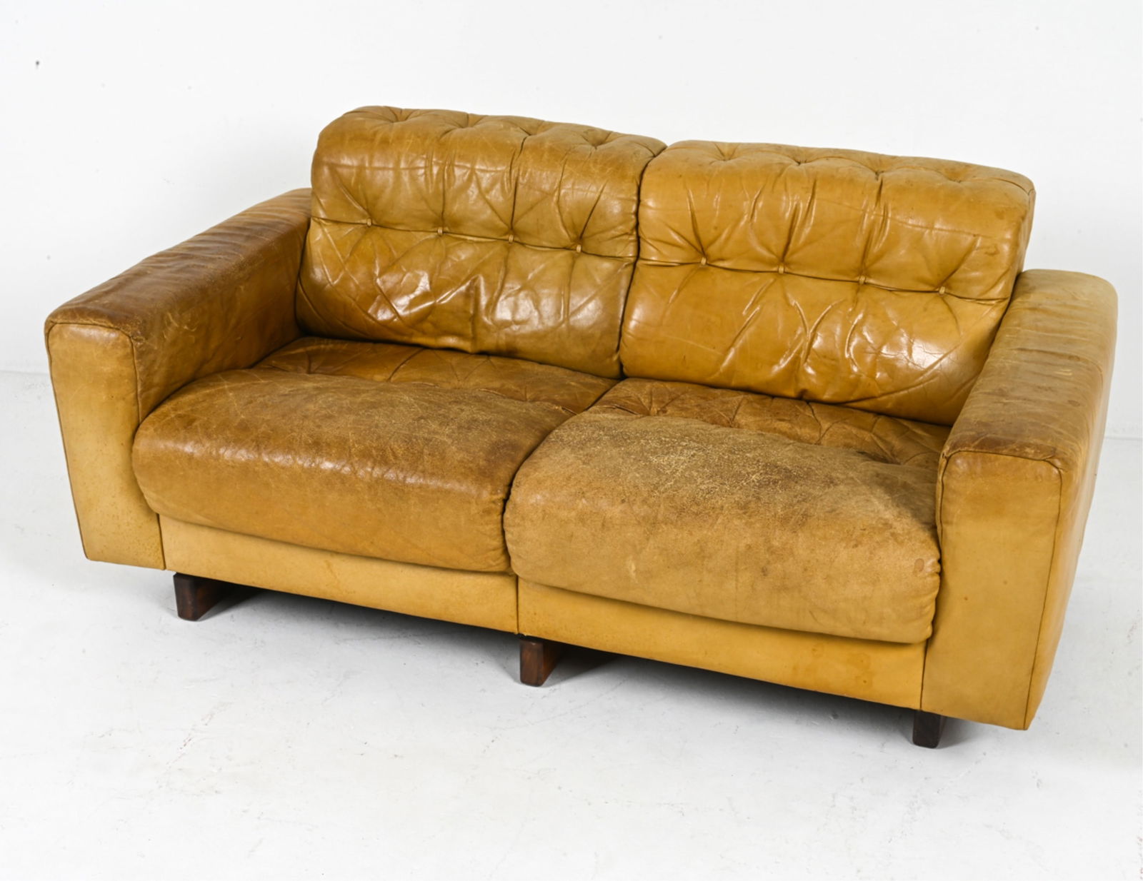 LEATHER SOFA BY DE SEDE, CIRCA 1970S: Model 'DS40'. Switzerland. Dimensions: H 27.5" x W 50.5" x D 29.75" x SH 15.5". Condition: Some wear and leather drying, more significant on seat cushions. Reupholstering recommended. Scuffs on arm en