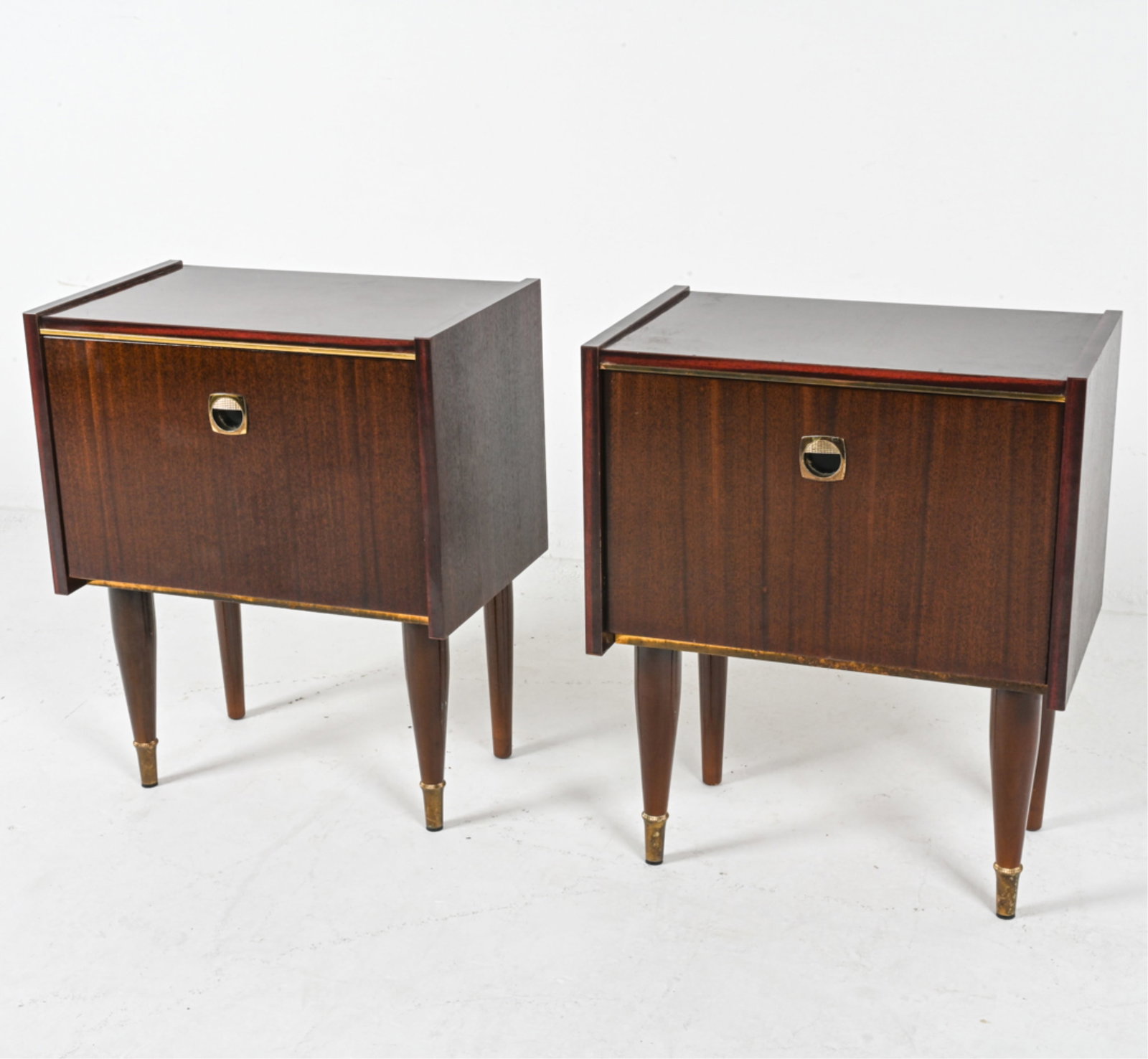 (2) MID-CENTURY ROSEWOOD NIGHTSTANDS: Rosewood veneer and brass hardware, accents. Mid 20th century. Dimensions: H 23.5" x W 19" x D 12". Condition: Minor scuffs to finish, some spots of tarnish to brass capped feet. Wear consistent with 