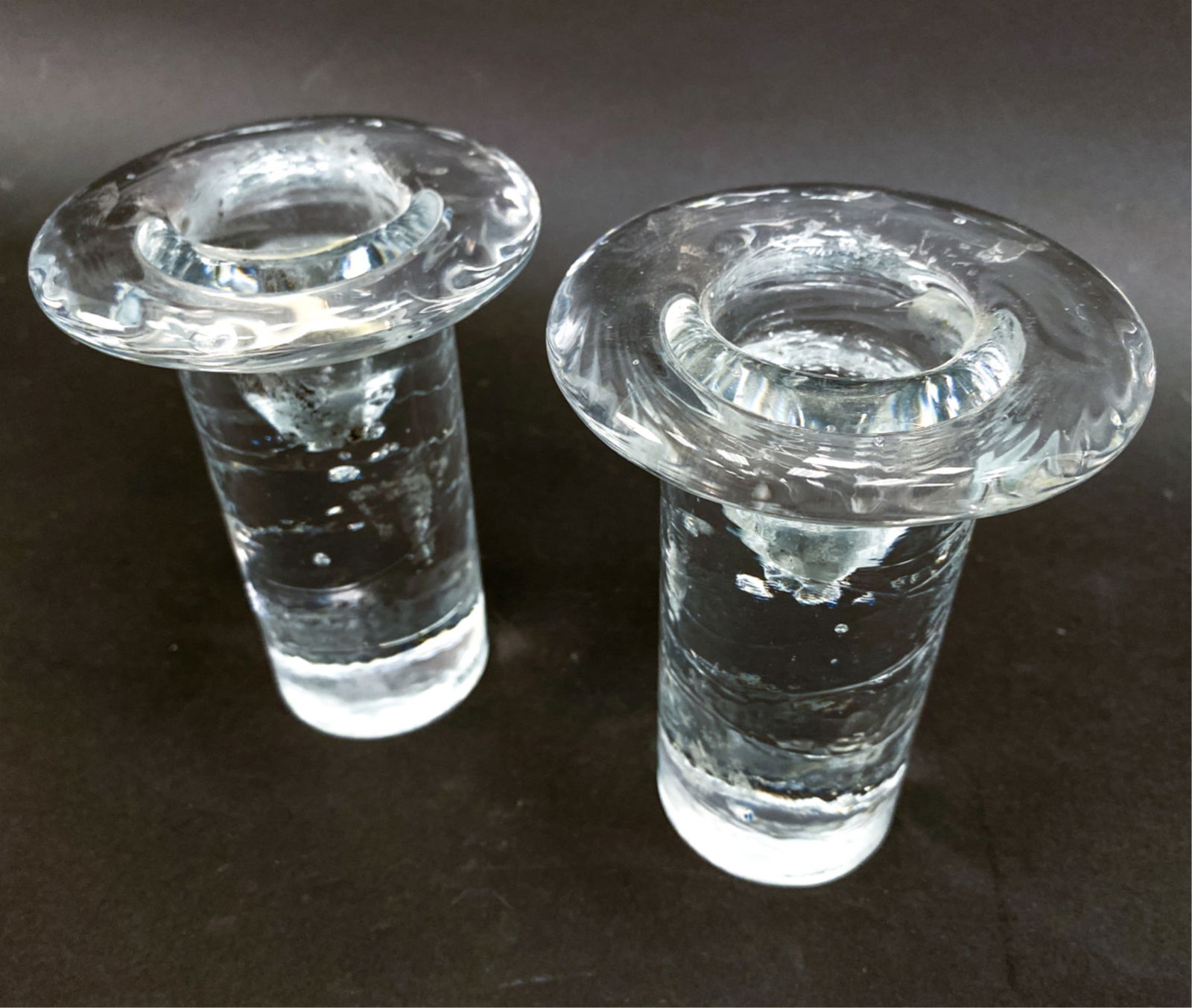 PAIR OF KOSTA BODA GLASS CANDLESTICKS: Both with Kosta Boda stickers on sides. Dimensions: H 5.25" x Dia 3.75" Condition: No issues to note. Wax residue inside holders.