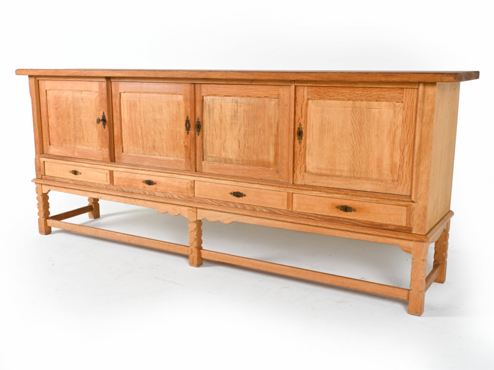 MANNER OF KJAERNULF DANISH OAK SIDEBOARD: Key is included. Carved in Brutalist style. Brass hardware. Circa 1970's. Dimensions: H 36" x W 89" x D 19" Conditions: A few minor water marks to top, some areas of minor discoloration. Wear consiste