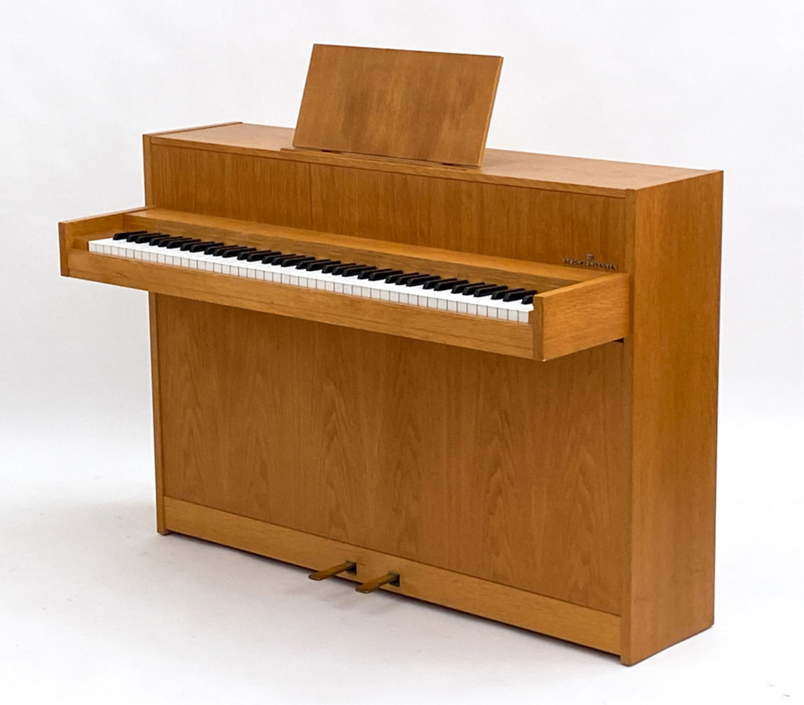 BRODR JORGENSEN OAK PIANO/PIANETTE, C. 1980'S: With a music stand fixed to top. Designer plaque on front above keys. Dimensions: H 35.75" x W 52" x D 21.75" Condition: Some finish wear. Plays without issues, may require tuning. Not professionally