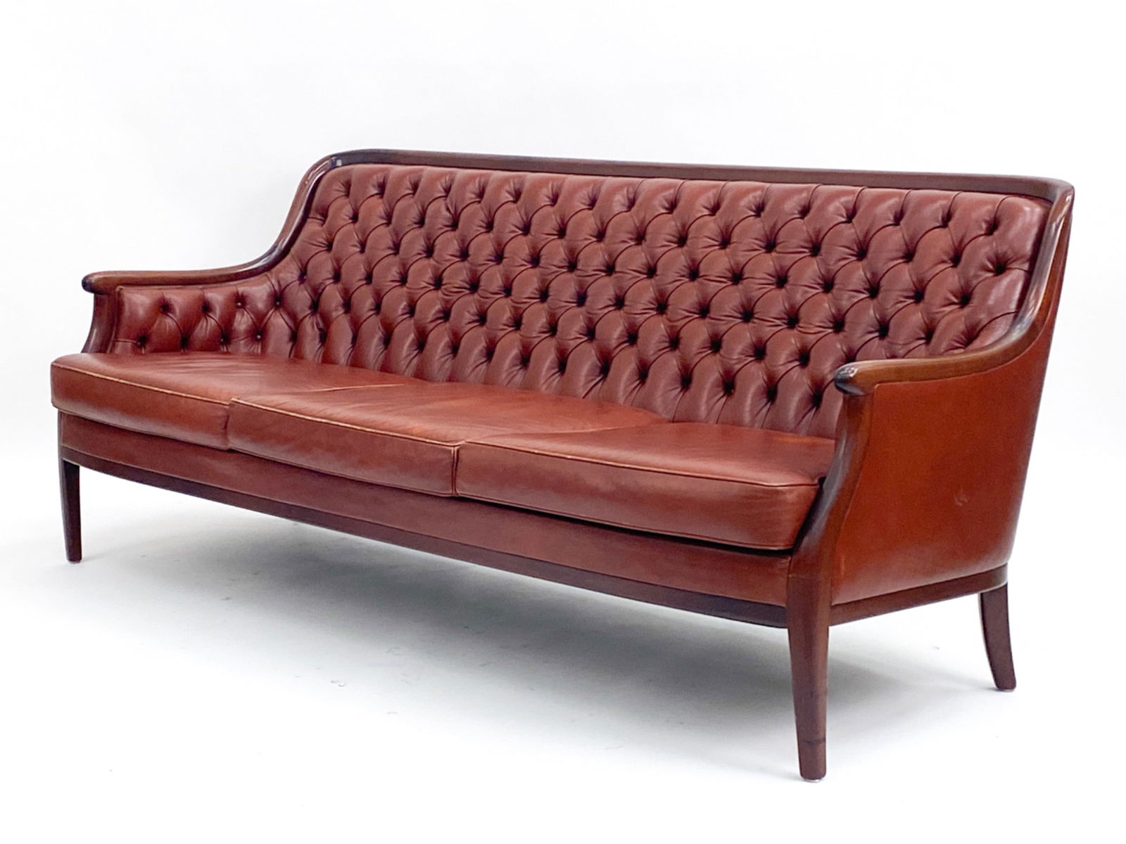CHESTERFIELD STYLE MAHOGANY & LEATHER SOFA, 1990'S: Rosewood sofa with tufted leather. Apparently unsigned. Dimensions: H 31" x W 75" x D 32" Condition: Finish wear consistent with age and use including some dings and scratches. Scuffs to leather and a