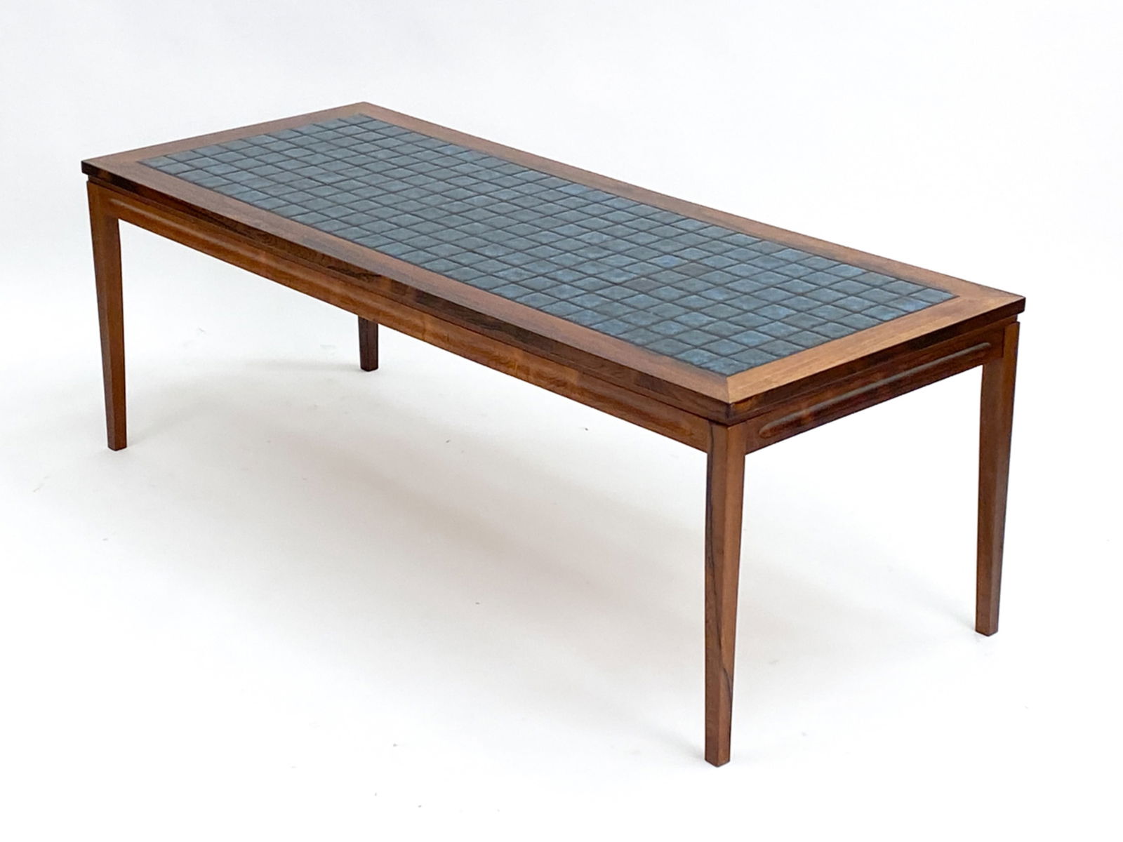 MID-CENTURY DANISH ROSEWOOD AND TILE COFFEE TABLE: Ceramic tiled top with a rosewood frame. Unsigned. Dimensions: H 20.75" x W 59" x D 24" Condition: Some finish wear including scratches.