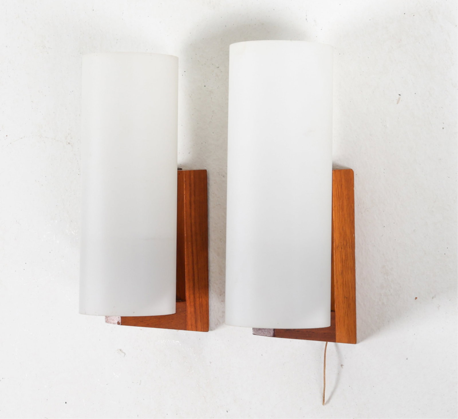 (2) DANISH TEAK AND GLASS WALL SCONCES: Circa 1960's. Dimensions: H 9" x W 3.25" x D 4.25". Condition: Some spots of discoloration on shades, holders, brass sockets. Minor scuffs and dings. Wiring untested, cords cut. Wear consistent with a