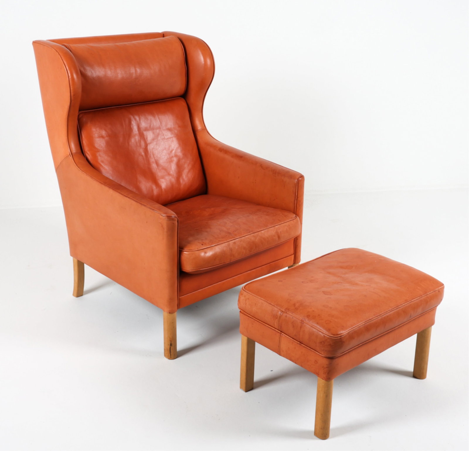 MANNER OF MOGENSEN LEATHER CHAIR AND OTTOMAN: Similar to Model 2204 wingback armchair. Oak legs. Paired with matching ottoman. Denmark, circa 1960's. Dimensions: (Chair) H 42" x W 28" x D 45" Seat height: 18" (Ottoman): H 15" x W 24" x D 17.5" Co