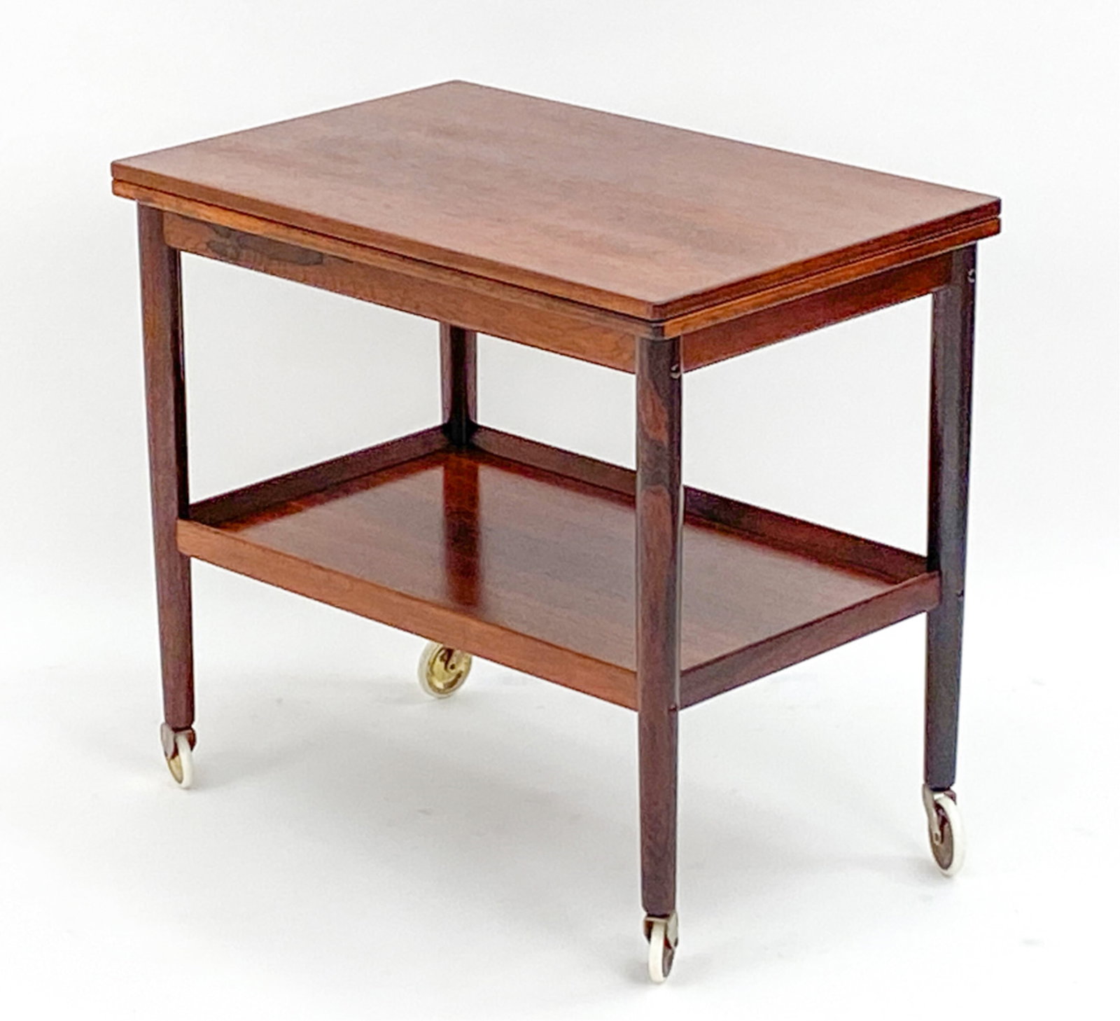 GRETE JALK DANISH ROSEWOOD BAR CART: Rosewood bar cart with hinged leaf top and lower storage panel on wheels. Dimensions: H 25" x W 27" x 17.5" Extended leaf top W 35.5" Condition: Wear includes. Dings, scratches to top and marks to und