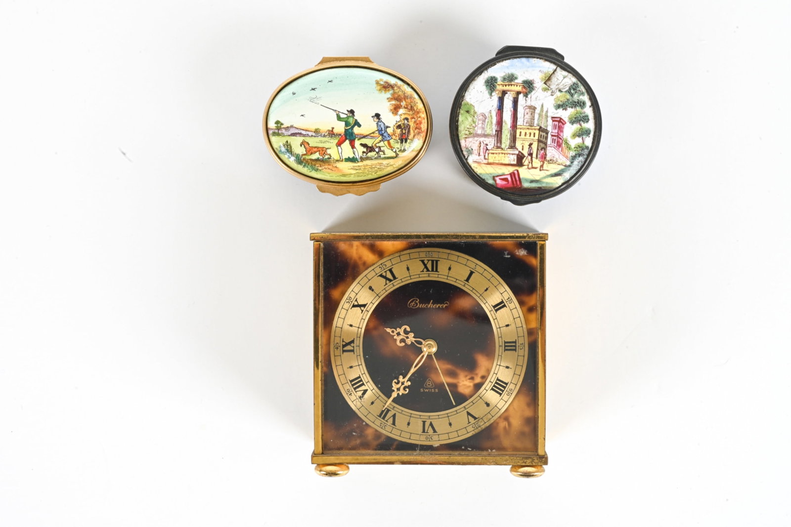 (3) DECORATIVE GROUPING, INC. SWISS BUCHERER CLOCK: Includes (1) Swiss carriage clock, signed Bucherer on face. Plus (2) miniature painted boxes. Dimensions: Clock H 3" x W 3" x D 1.5". Condition: Timekeeping on clock untested, missing two feet, minor