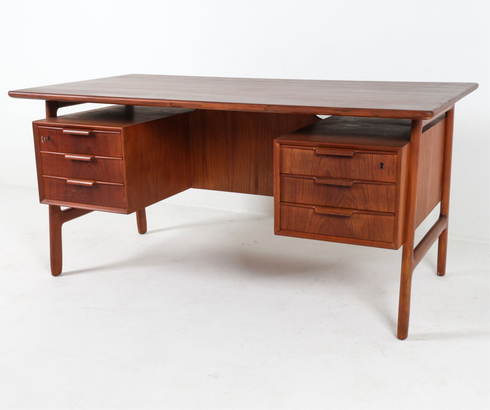 GUNNI OMANN 'MODEL 75' DANISH TEAK DESK: For Omann Jun. Floating top design. Key included. Circa 1960's. Dimensions: H 29" x W 60" x D 31.5". Condition: Faint scuff marks on drawer front. Some discoloration on back shelves. Wear consistent w