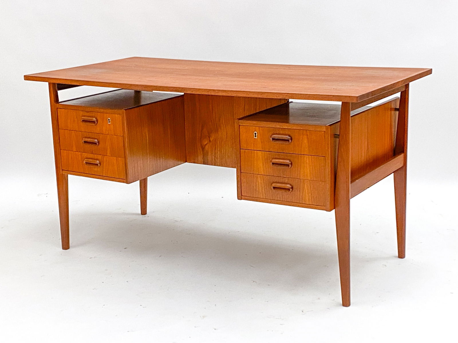 DANISH TEAK DESK MANNER OF ARNE VODDER. C.1960'S: No key. Freestanding/ floating desk in the manner of Arne Vodder. Front drawers and back bookshelf/ shelf. Dimensions: H 28.75"x W 55"x D 27.25" Condition: Minor marks to top. Scattered scratches and