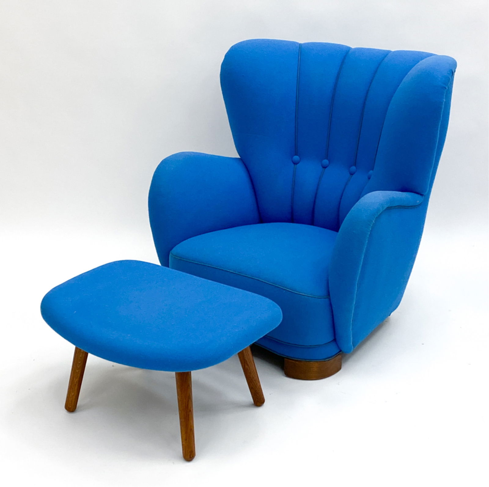 MANNER OF FLEMMING LASSEN WINGBACK CHAIR C.1940'S: 1940s Channeled and tufted high back chair along with with a different maker 1960s ottoman. Dimensions: (Chair) H 36"x W 35" x D 27" Seat height: 14" (Ottoman) 13.5"x W 27"x D 20" Condition: Minor fad