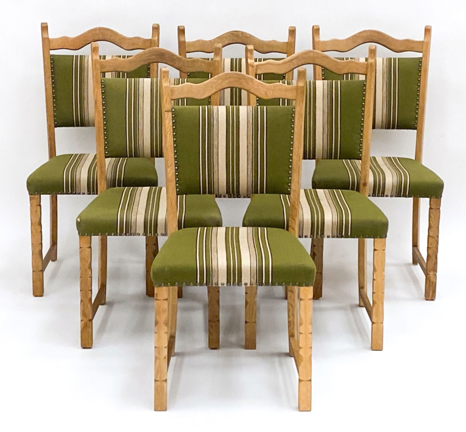 6 DANISH OAK DINING CHAIRS IN MANNER OF KJAERNULF: In the manner of Henning Kjaernulf. C.1970's Carved legs with studs to upholstery. Dimensions:H 37" x W 18"x D 17.5" Seat Height: 19" Condition: Tear to corner of upholstery. Minor nicks and scratches
