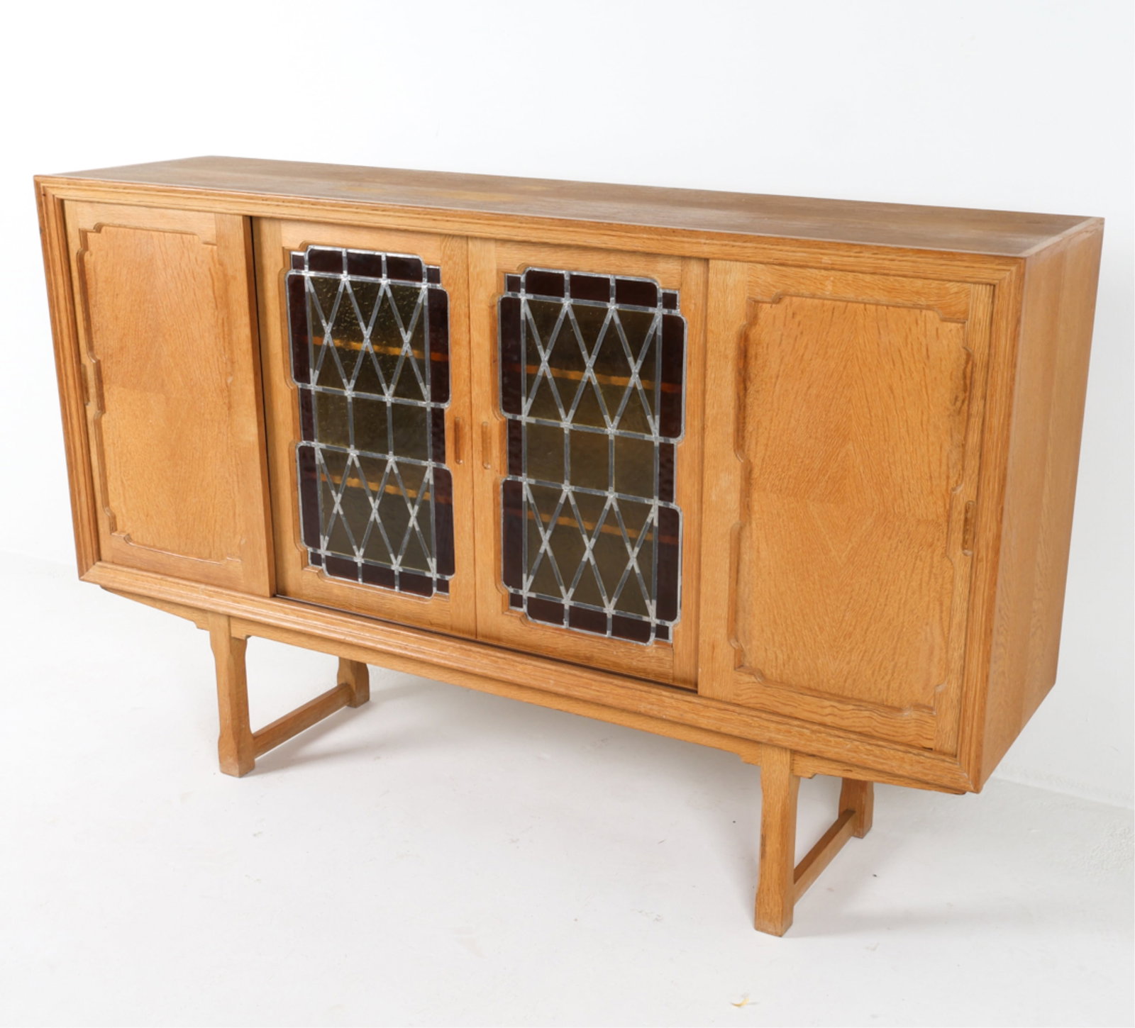 DANISH OAK SIDEBOARD W/ LEADED GLASS DOORS,1960'S: With stained glass panel sliding doors. Recessed wooden sliding doors. Scooped cabinet door pulls. Dimensions: H 45" x W 70.5" x D 18.25". Condition: Areas of sun fading on top, faint water rings. Som