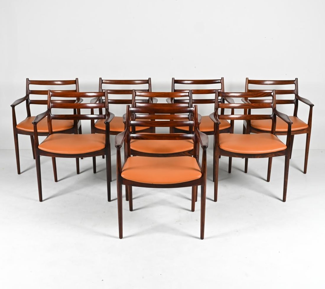(8) RARE ROSEWOOD DINING CHAIRS ATTR. ARNE VODDER: Indulge in the timeless allure of Scandinavian design with this exquisite set of eight dining armchairs, a masterpiece from the esteemed Arne Vodder. Characterized by an elegant ladder-back frame, eac