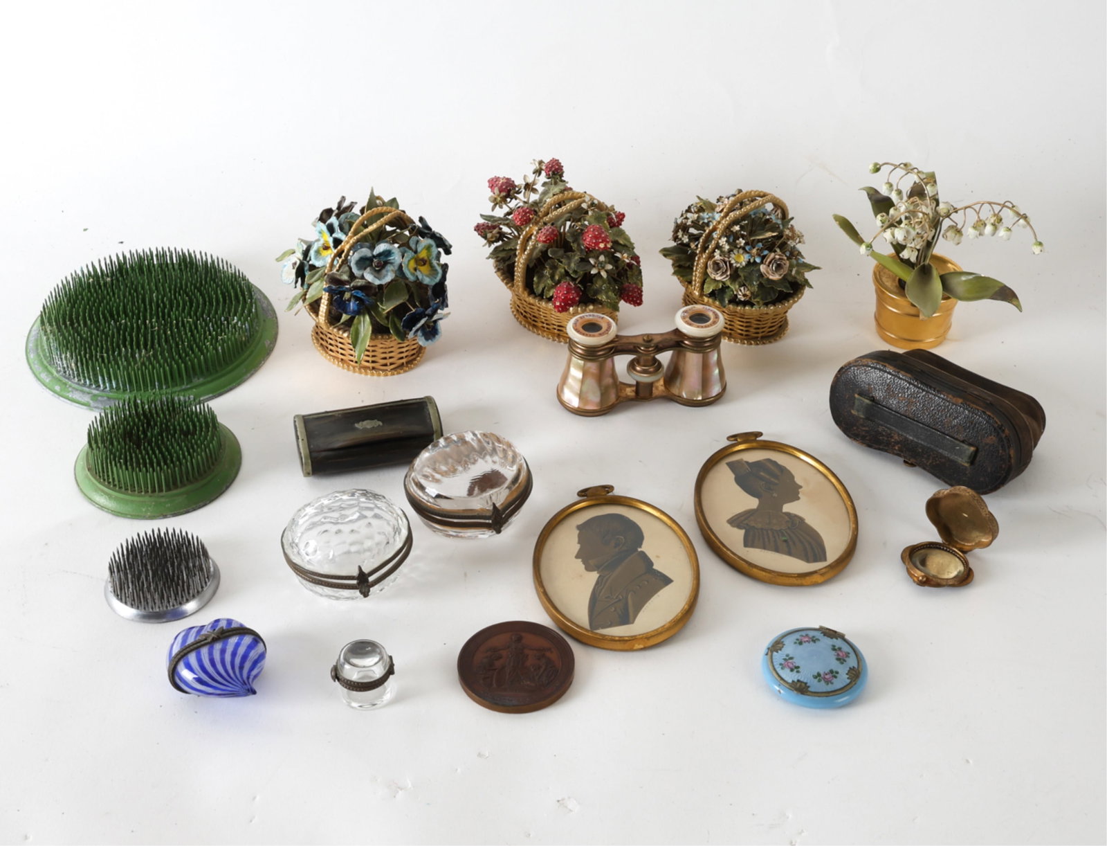 DECORATIVE GROUPING INCL. GLASS BOXES: Brass and enamel flowers, flower frogs. Paper cut out silhouette portraits. Glass trinket boxes and thimble box, art glass pill box. A bone snuff box, a guilloche enamel powder compact by D.F.Briggs,