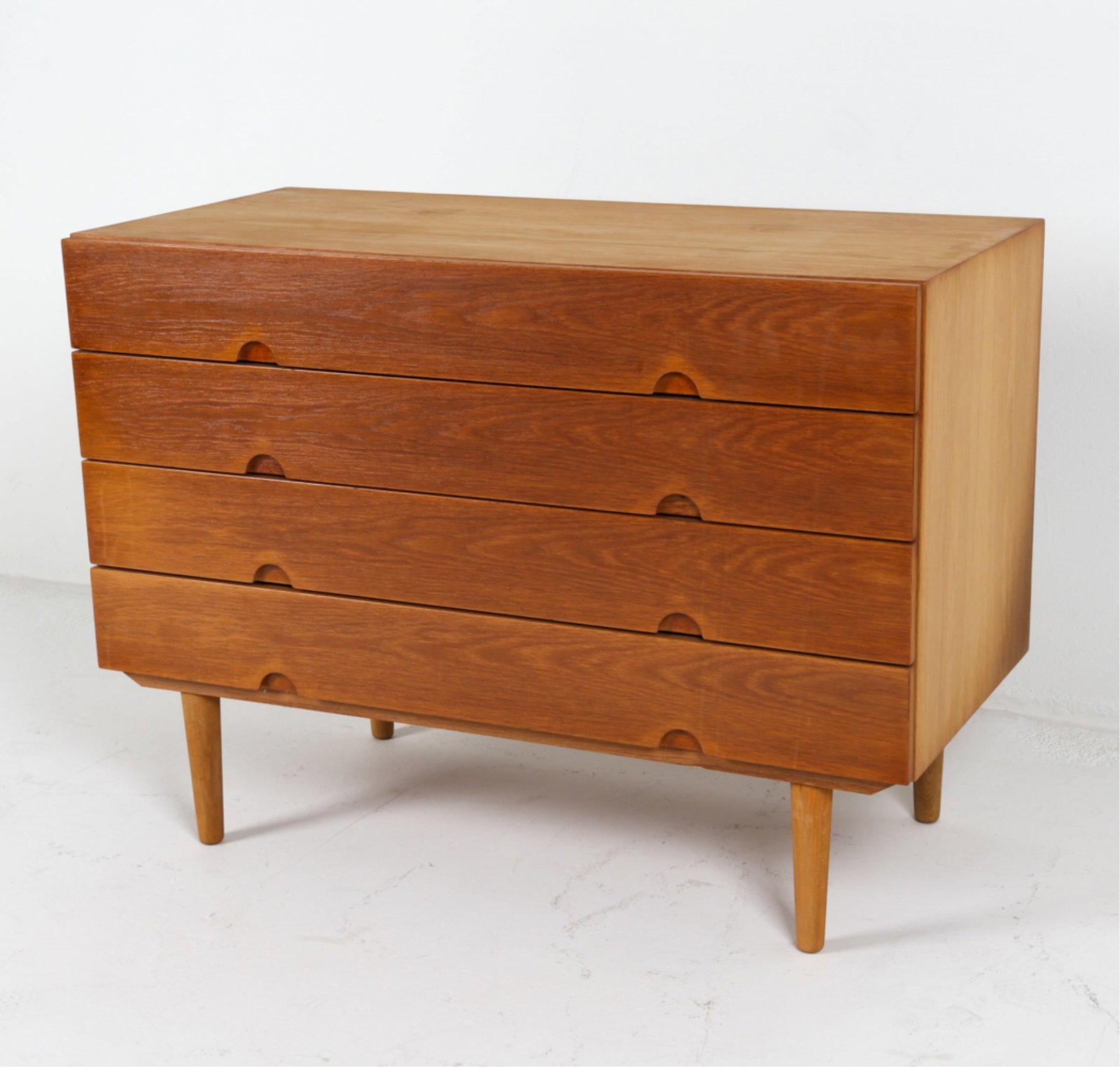 DANISH OAK CHEST OF DRAWERS ATTR. HW KLEIN: For Bramin. Apparently unmarked. Subtle curved recesses as drawer pulls. Tapered legs. Circa 1960's. Dimensions: H 29" x W 39.5" x D 18.75". Condition: Some sun fading on top. Slight tobacco odor. Wea