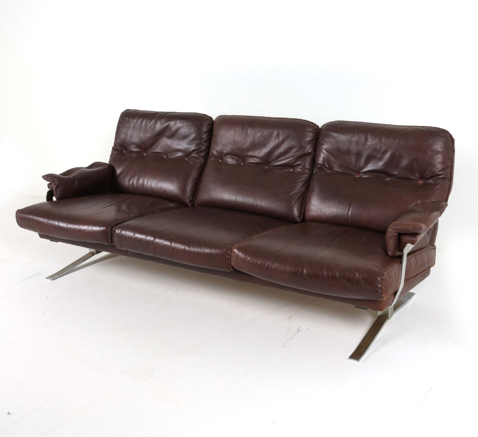 ATTR. ARNE NORELL LEATHER AND STEEL SOFA, C.1970'S: Tufted leather cushions. Braided accent trim. Denmark. Apparently unsigned. Dimensions: H 30" x W 79" x D 30" x SH 15". Condition: Some scuffs and dings to steel. Few rubs to leather. Wear consistent