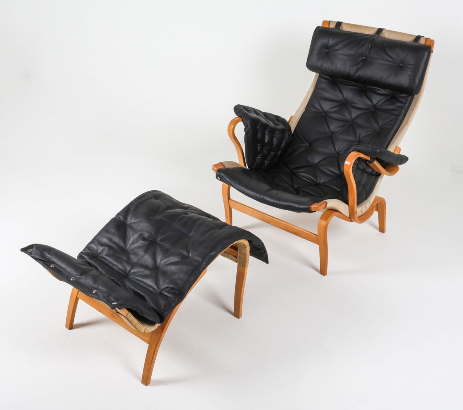 BRUNO MATHSSON 'PERNILLA' EASY CHAIR & OTTOMAN: For Firma Karl Mathsso. Stamp to chair and ottoman. Bentwood beech frame. Black leather cushions Canvas backings. Dimension: (chair) H 37" x W 33.5" x D 38" (Ottoman) H 17.5" x W 20"x D 25.5" Conditio
