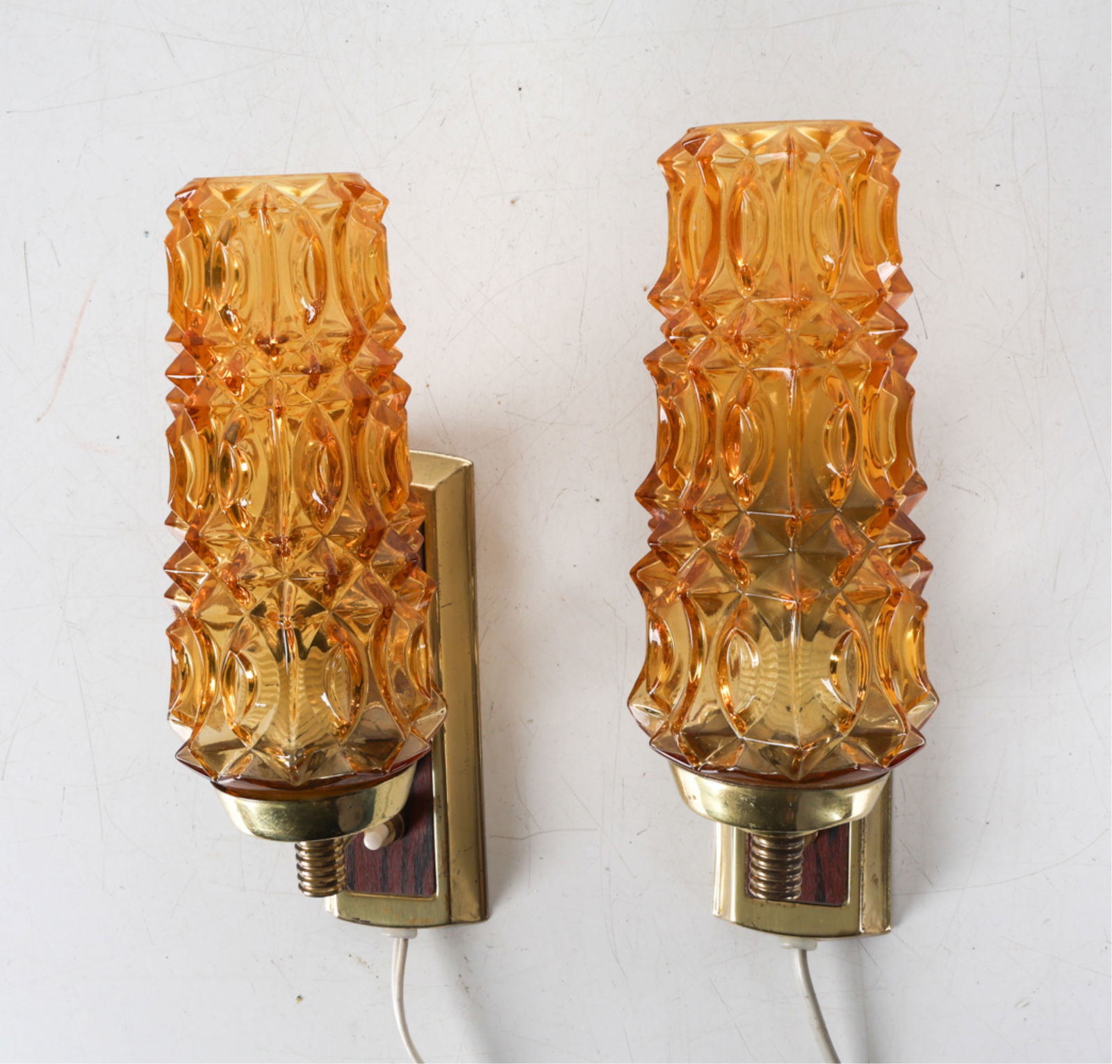 PAIR OF LAONI-BELYSNING GLASS & BRASS WALL SCONCES: Textured amber glass shades with brass fittings. Denmark, circa 1960's. Dimensions: H 10" x W 3" x D 5". Condition: Wiring untested, requires rewiring. Few scuffs and scratches to brass. Wear consiste