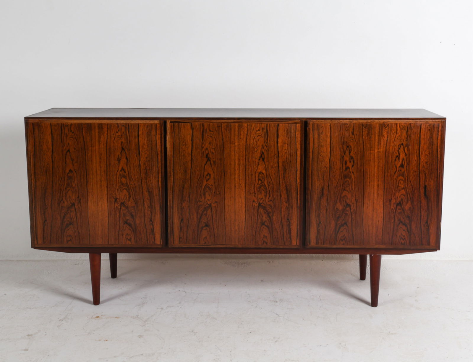 OMANN JUN MODEL 30 DANISH ROSEWOOD SIDEBOARD: Tag inside cabinet . Adjustable shelves. Tapered legs. Denmark, Circa 1970's. Dimensions: H 34" x W 70.5" x D 17.25". Condition: Scratches and marks to top. Wear consistent with age and use. DMK073