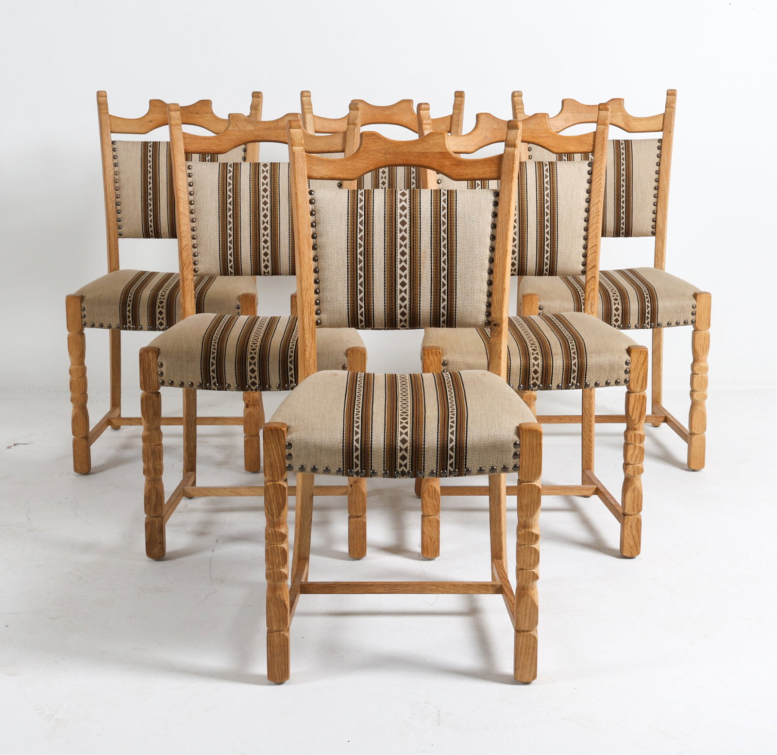(6) KJAERNULF STYLE DANISH OAK DINING CHAIRS: Patterned wool fabric upholstery with brass tacks. Dimensions: H 37" x W 17" x D 18" x SH 17.5". Condition: Minor scuffs and dings to wood. Wear consistent with age and use. DMK003