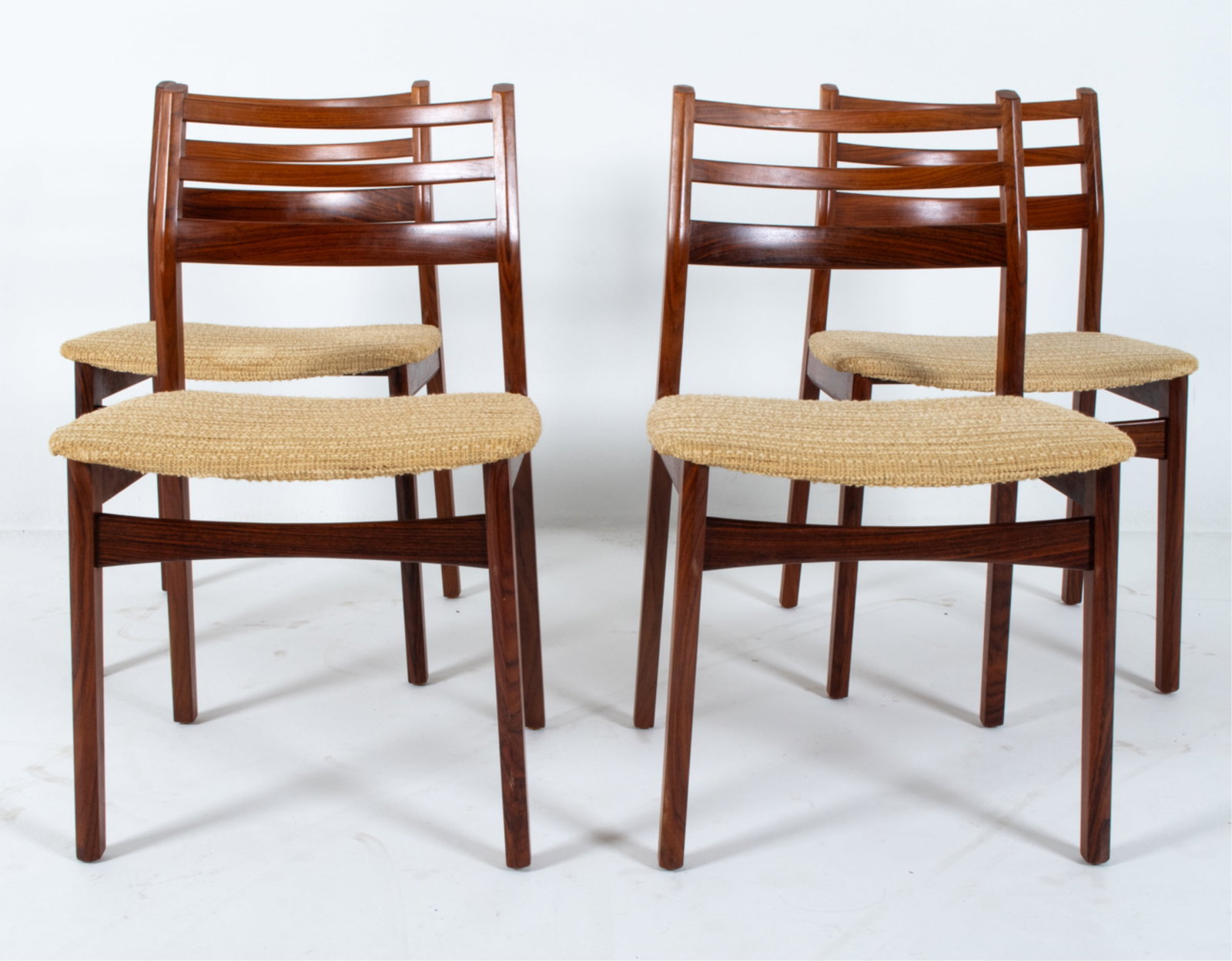 (4) DANISH ROSEWOOD AND WOOL DINING CHAIRS: Ladderback design. Cream toned woven wool upholstered seats. Dimensions: H 32.5" x W 19.75" x D 16" x SH 17.25". Condition: Few scuffs and rubs to wood. Slight tobacco odor. Wear consistent with age a