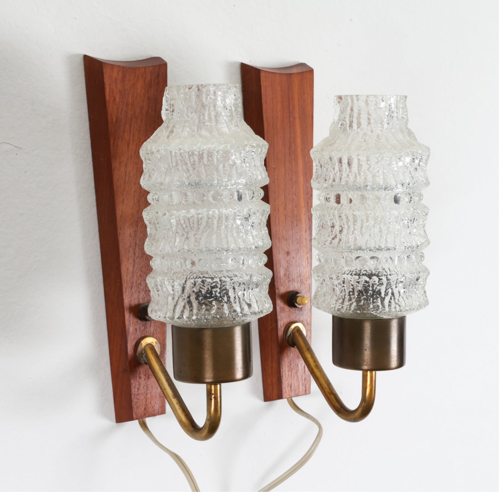 (2) DANISH TEAK AND CRYSTAL GLASS WALL SCONCES: Circa 1970's. Dimensions: H 10" x W 3.25" x D 5.25". Condition: Crack in one shade, pictured. Wiring untested, European plug. Wear consistent with age and use. DMJ130