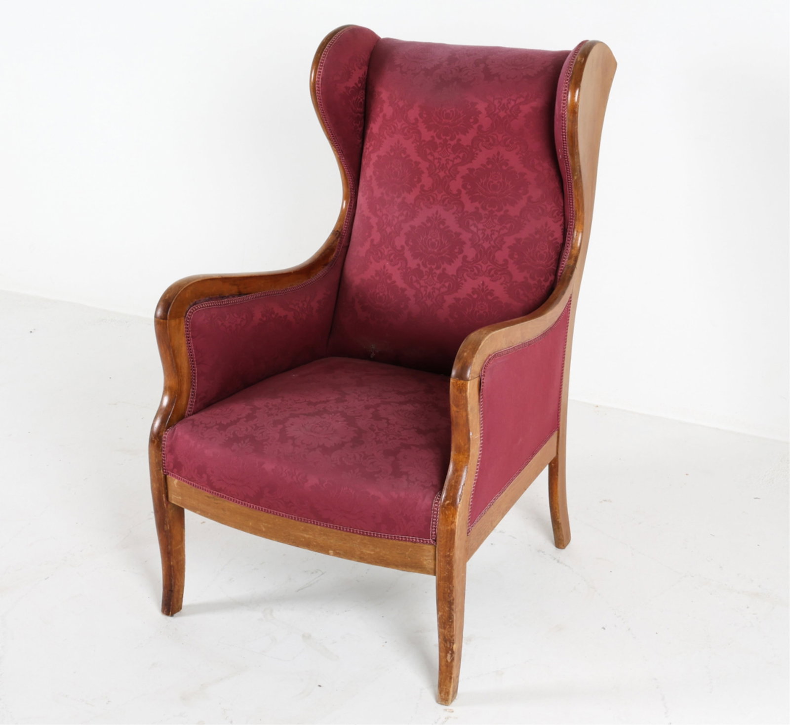 WINGBACK ARMCHAIR BY FRITS HENNINGSEN, C.1940'S: Iconic curved seat back, curves continuously into arms and legs. Mahogany. Fabric upholstery. Dimensions: H 41.75" x W 25" x D 33" x SH 16". Conditions: Wear consistent with age and use, a few scatter
