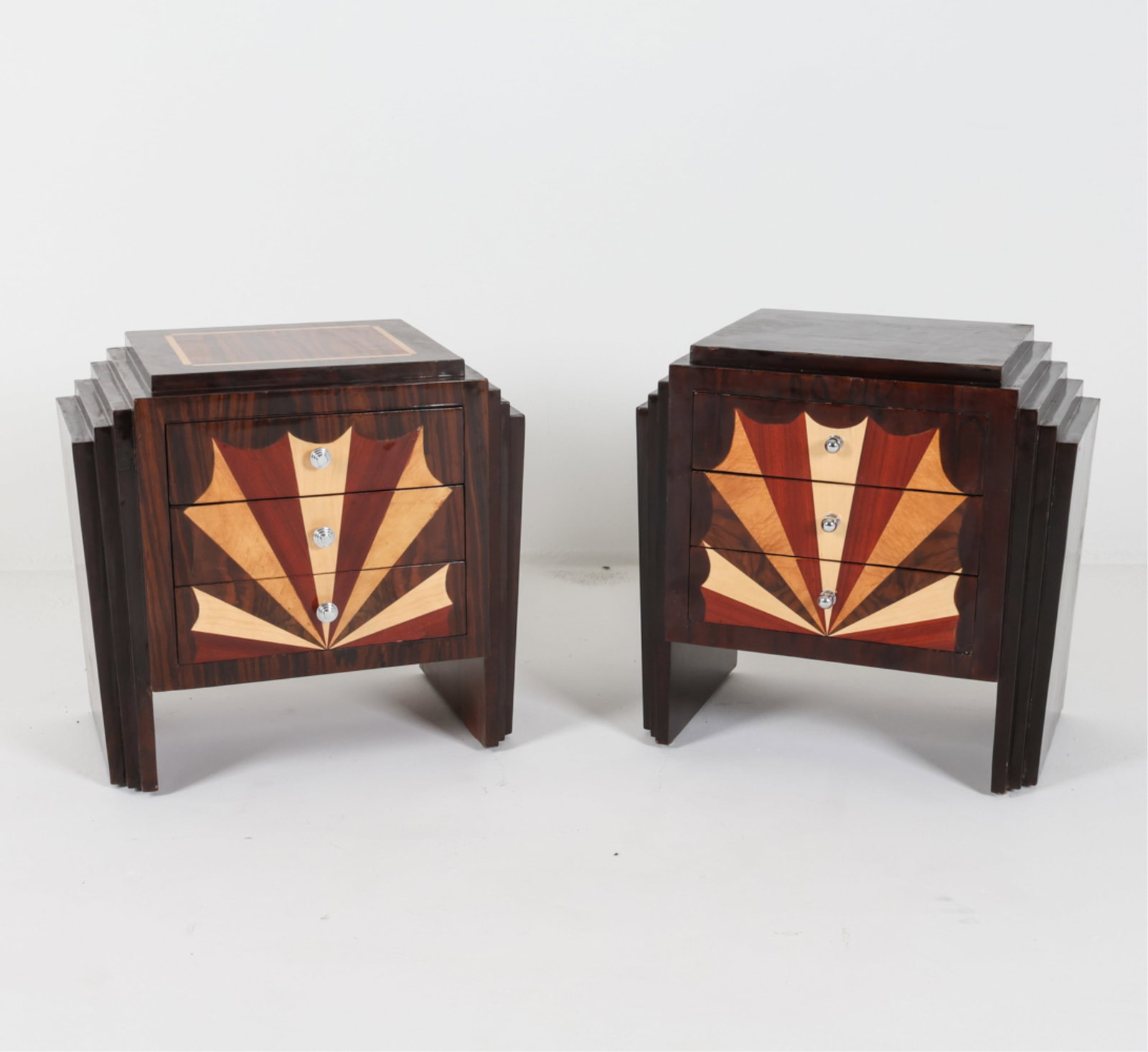 (2) ART DECO STYLE NIGHTSTANDS W/ INLAID WOODS: Multiple wood inlay with pinwheel decoration on front. Waterfall-tiered profile. One with inlay design on top. Mid-to late 20th century. Dimensions: H 23" x W 24.25" x D 15.5". Condition: Some bucklin