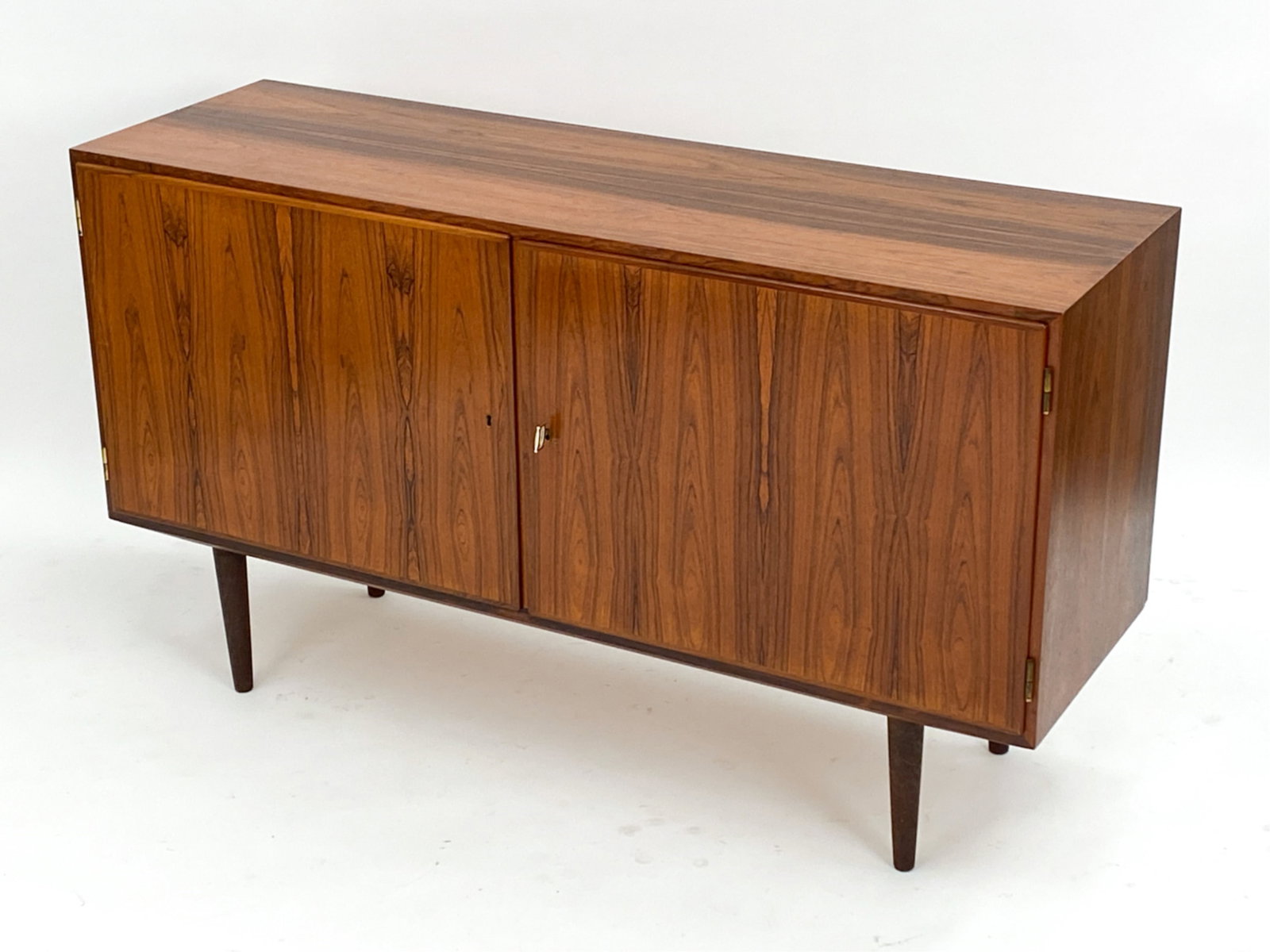 HUNDEVAD DANISH ROSEWOOD SIDEBOARD C.1960'S: With key. Adjustable shelves. Marked to backside and interior cabinet. Dimensions: H 31.25" x W 54.5"x D17" Condition: Scuffs, nicks and dings to top and edges. Lower corner to back proper left side h