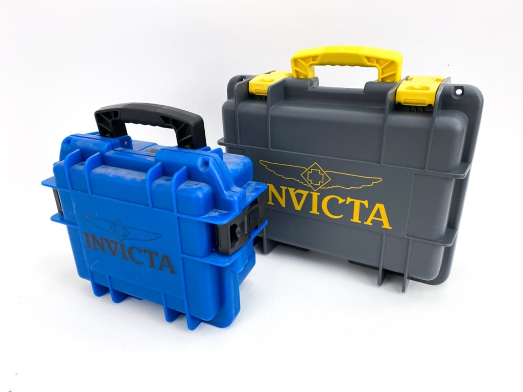 (2) INVICTA WATCH CASES: A grey and yellow case that houses 8 watches and a black and blue case that houses 3 watches. Dimensions: (Larger case) H 6.75" x W 15" x D 12" Condition: Cases with handing marks.