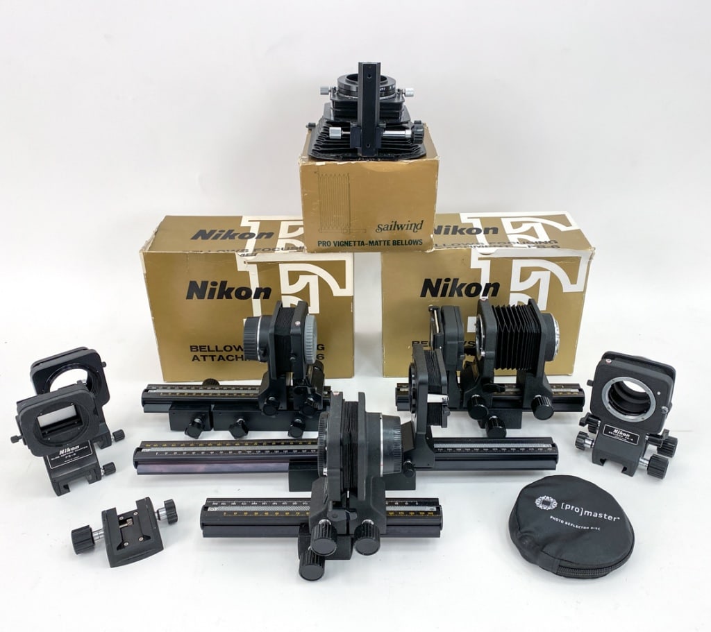 GROUPING OF NIKON EXTENSION BELLOWS, ETC.: With Nikon and Sailwind bellows, three in original boxes. Dimensions: (Largest) H 7.75" x 10.5" x D 5.25" Condition: Minor nicks to accessories, wearing to edges to boxes consistent with age and use.