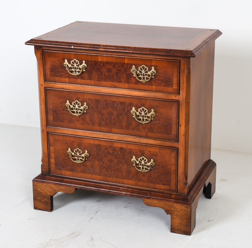 GEORGIAN STYLE BURL WOOD NIGHTSTAND: With brass hardware. Tag to backside, made in England. Dimensions: H 27.25 x W 25.25" x D 16.25" Condition: Cracking to edges. Bubbles in top finish. Wear consistent with age and use.