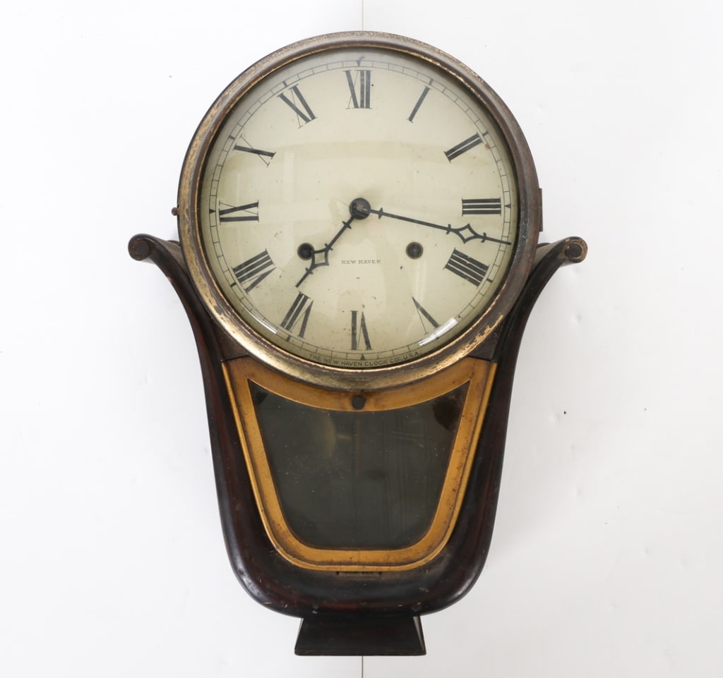 NEW HAVEN MEDENA MOHAGANY WALL CLOCK: With Key. Labeled to backside. Mahogany frame. Convex glass panel to clock face. Dimensions: H 13.5" x W 11.25" x D 4.5" Condition: Convex glass loose within frame. Scuffs, marks and nicks to mahogany