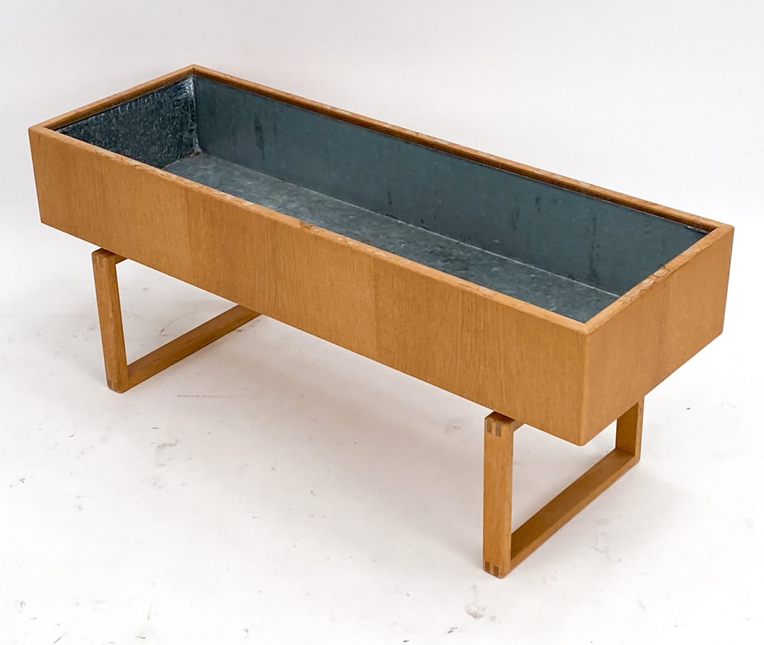 KAI KRISTIANSEN FOR AKSEL KJERSGAARD OAK PLANTER: With removable planter tray. Circa 1960's. Unmarked. Dimensions: H 16.5" x W 39.5" x D 13.75" Condition: With some soiling to plant tray. Water marks along top edge of oak frame. PK015