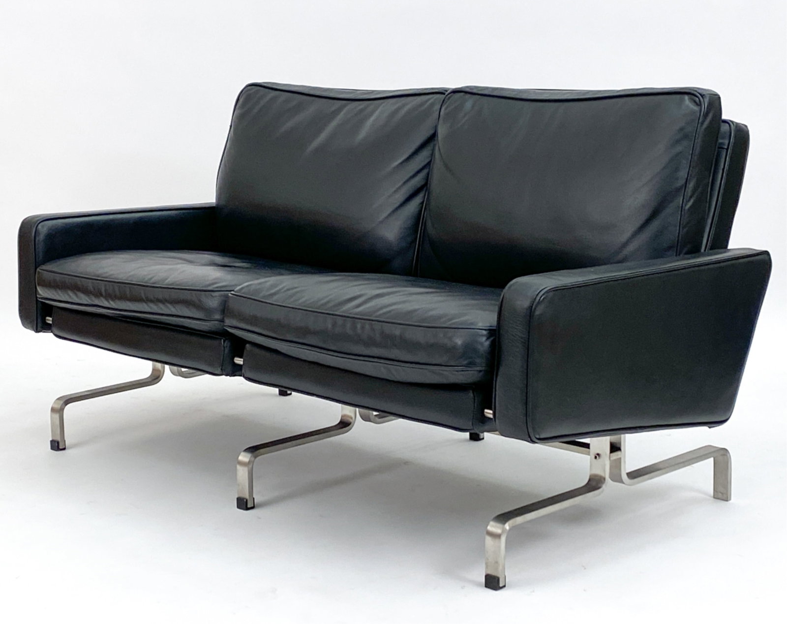 POUL KJAERHOLM STYLE DANISH LEATHER & STEEL SOFA: 2-seater sofa in leather with steel legs, in the style of Poul Kjaerholm. Unsigned. Circa 1980's. Dimensions: H 28" x W 55" x D 29" x SH 16" Condition: Some scuffs to leather. missing a foot pad. JE02