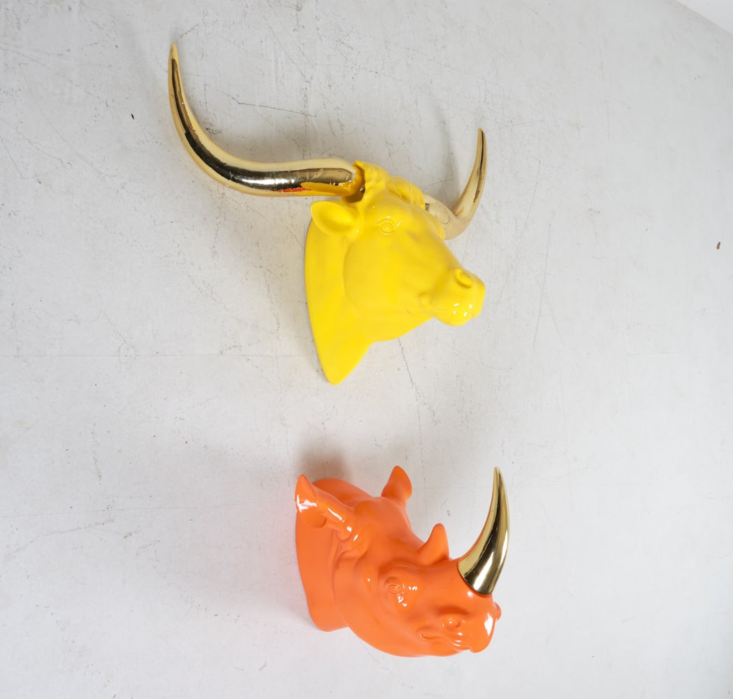 PAIR OF C. WONDER ANIMAL HEAD WALL SCULPTURES: From the C. Wonder store. Fiberglass. Contemporary. Horns are removable. Dimensions: (Ox) H 28" x W 34" x D 15". Condition: Scuffs, scratches and marks on surface and horns. Crack in rhino horn near b