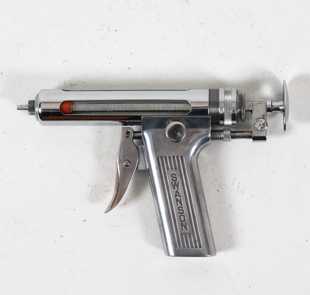 SWANSON VACC-OMATIC VACCINATION GUN C. 1950'S: With original schematics and instructions. Dimensions: Gun H 5.25" x W 8.5". Condition: Few scuffs and scratches. Box is heavily worn. Wear consistent with age and use.