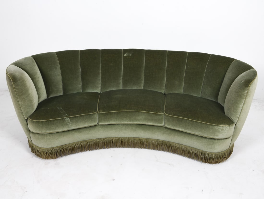 DANISH CHANNEL BACK MOHAIR BANANA SOFA C. 1950'S: Channel back upholstery with fringe along bottom. Oak legs. Dimensions: H 25" x W 75" x D 35" x SH 14.5". Condition: Scuff or indentation to mohair on seat back. Scratches to feet. Wear consistent wit