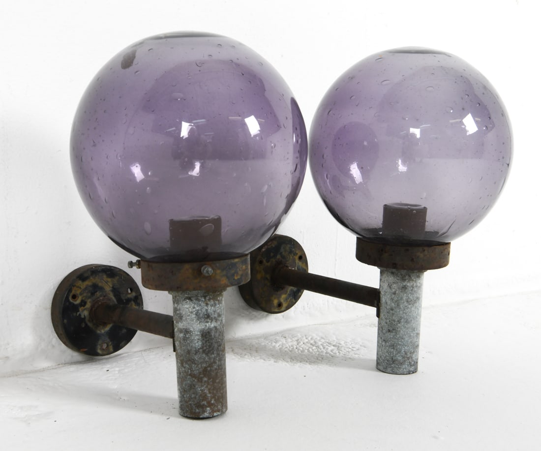 PAIR DANISH PURPLE GLASS GLOBE OUTDOOR SCONCES: Denmark, circa 1970's. Dimensions: Shade Dia. 8.5". D 10.75". Condition: Wiring untested. Evident oxidation to metal. Scuffs and scratches to metal. Wear consistent with age and outdoor use. DMM165