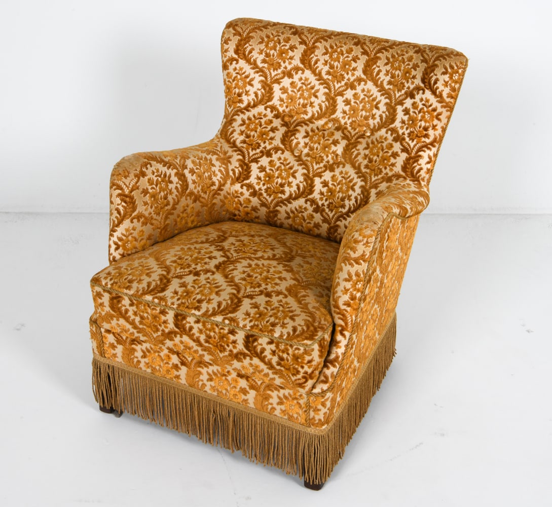 DANISH DAMASK PATTERN LOUNGE CHAIR C. 1960'S: Textured damask pattern with fringe along base. Dimensions: H 31.5" x W 25.25" x D 23" x SH 15". Condition: Few worn spots through fabric on arms. Slight tobacco odor. Some sun fading. Wear consistent